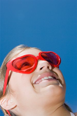 simsearch:625-01748263,k - Low angle view of a girl wearing red sunglasses and smiling Stock Photo - Premium Royalty-Free, Code: 625-01749042