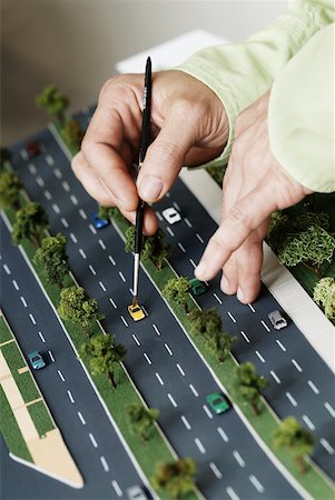 Close-up of a person's hand placing a car on a model of highway Stock Photo - Premium Royalty-Free, Code: 625-01749088