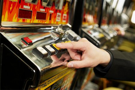 Close-up of a person's hand playing on a slot machine Stock Photo - Premium Royalty-Free, Code: 625-01749122