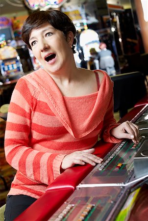 Mature woman playing on a slot machine and looking surprised Stock Photo - Premium Royalty-Free, Code: 625-01749156