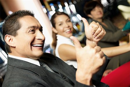 Side profile a mature man showing a thumbs up sign with his daughter beside him at a casino Stock Photo - Premium Royalty-Free, Code: 625-01749163