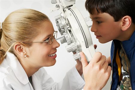 Side profile of a female optometrist examining a boy's eye Stock Photo - Premium Royalty-Free, Code: 625-01749227