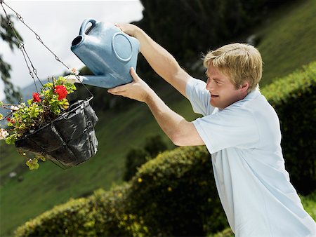 Side profile of a mid adult man watering a potted plant Stock Photo - Premium Royalty-Free, Code: 625-01749420
