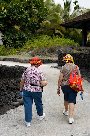 Rear view of two women walking on a walkway, Puuhonua O Honaunau National Historical Park, Kona Coast, Big Island, Hawaii Islands Stock Photo - Premium Royalty-Free, Code: 625-01751145