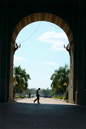 simsearch:625-01752795,k - Side profile of two people walking on the footpath in front of an arch, Victoria Memorial, Laos Stock Photo - Premium Royalty-Free, Code: 625-01752897