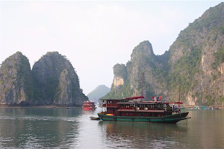 simsearch:625-01753066,k - Tourboats dans une baie rock formations en arrière-plan, la baie d'Halong, Vietnam Photographie de stock - Premium Libres de Droits, Code: 625-01753066