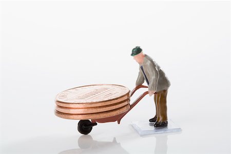 Figurine of a manual worker carrying coins on a wheelbarrow Stock Photo - Premium Royalty-Free, Code: 625-02265963