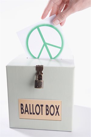 Close-up of a person's hand inserting a world peace symbol vote into a ballot box Stock Photo - Premium Royalty-Free, Code: 625-02266016