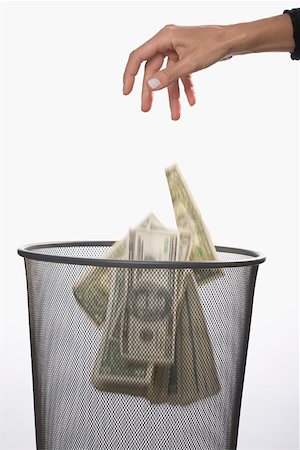Close-up of a person's hand throwing US dollar bills in a garbage bin Stock Photo - Premium Royalty-Free, Code: 625-02266019