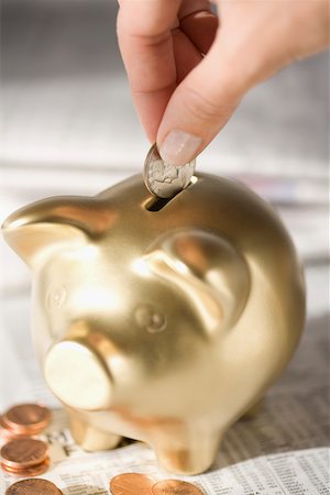 piggy bank hand - Close-up of a person's hand putting a coin into a piggy bank Stock Photo - Premium Royalty-Free, Code: 625-02266078