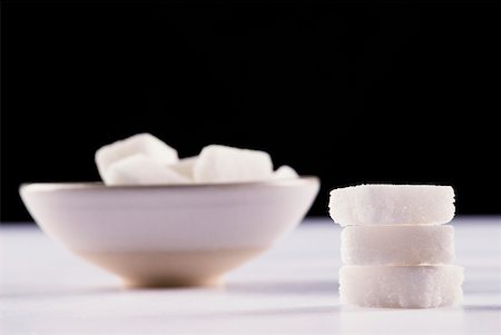 Stack of sugar cubes and a bowl of sugar cubes in the background Foto de stock - Royalty Free Premium, Número: 625-02266172