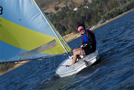 Young woman sitting in a sailboat and smiling Stock Photo - Premium Royalty-Free, Code: 625-02266453