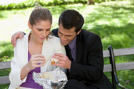 Businessman and a businesswoman having food on a park bench Stock Photo - Premium Royalty-Free, Code: 625-02266467