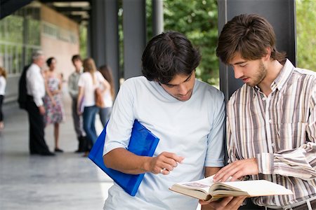 sharing files - Two young men looking at a book in a corridor Stock Photo - Premium Royalty-Free, Code: 625-02266489