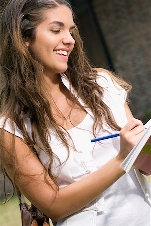 excited college student with books - Close-up of a young woman writing and smiling Stock Photo - Premium Royalty-Free, Code: 625-02266714