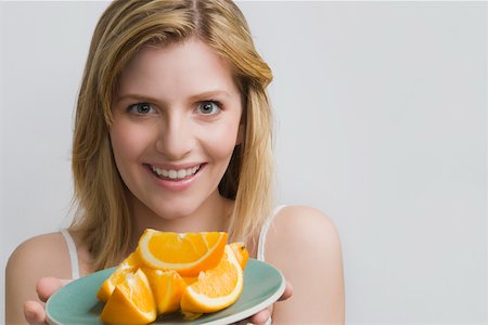 Portrait of a teenage girl holding a plate of oranges and smiling Stock Photo - Premium Royalty-Free, Code: 625-02266777