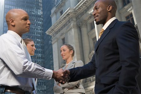 Side profile of two businessmen shaking hands with two businesswomen smiling Stock Photo - Premium Royalty-Free, Code: 625-02266854