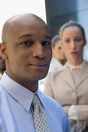 simsearch:625-02267530,k - Close-up of a businessman smiling with two businesswomen in the background Stock Photo - Premium Royalty-Free, Code: 625-02266863