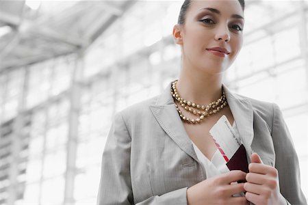 Portrait of a businesswoman putting a passport with an airplane ticket in her coat's pocket Stock Photo - Premium Royalty-Free, Code: 625-02266907