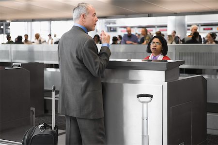 Side profile of a businessman standing at a ticket counter in an airport Stock Photo - Premium Royalty-Free, Code: 625-02266912