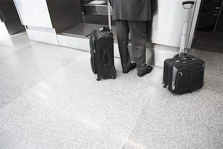 simsearch:625-02932602,k - Vue en coupe basse d'un homme d'affaires permanent avec ses bagages dans un aéroport Photographie de stock - Premium Libres de Droits, Code: 625-02266946