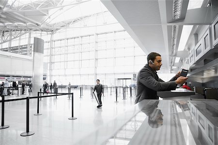 simsearch:625-02932602,k - Profil de côté d'un homme d'affaires permanent à un comptoir dans un aéroport Photographie de stock - Premium Libres de Droits, Code: 625-02266940