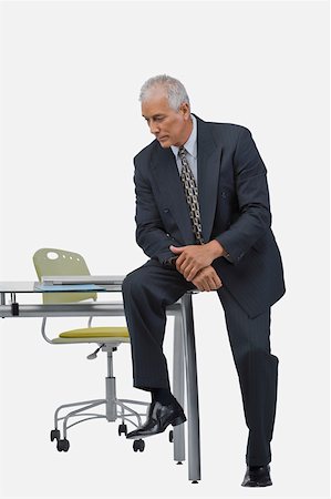 Businessman sitting at a desk in an office and thinking Stock Photo - Premium Royalty-Free, Code: 625-02267015