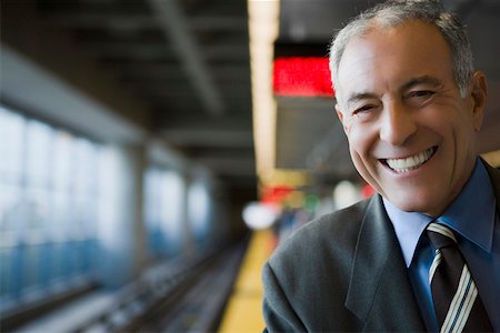 senior man portrait formal - Portrait of a businessman smiling at a subway station Stock Photo - Premium Royalty-Free, Code: 625-02267041