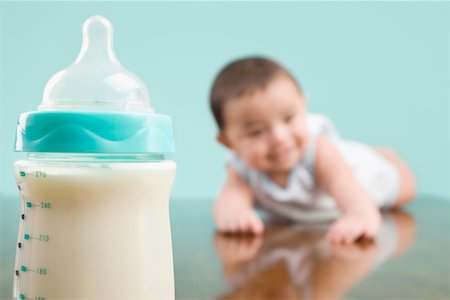 Close-up of a milk bottle with a baby boy in the background Stock Photo - Premium Royalty-Free, Code: 625-02267135