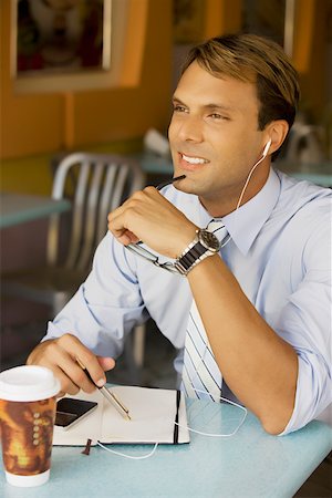 Businessman listening to an MP3 player and smiling Stock Photo - Premium Royalty-Free, Code: 625-02267190
