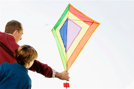 people flying kites in the sky - Rear view of a mid adult man with his son flying a kite Stock Photo - Premium Royalty-Free, Code: 625-02267203