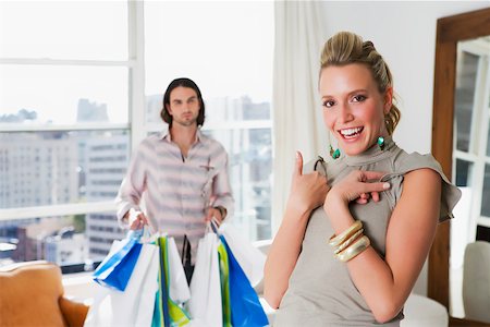 simsearch:625-02266783,k - Young woman laughing with a young man holding shopping bags behind her Stock Photo - Premium Royalty-Free, Code: 625-02267315