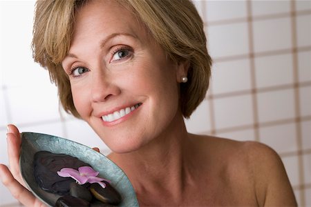 Portrait of a mature woman holding a bowl of pebbles and a flower Stock Photo - Premium Royalty-Free, Code: 625-02267394