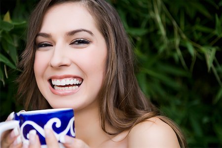 Portrait of a young woman holding a tea cup and smiling Stock Photo - Premium Royalty-Free, Code: 625-02267399