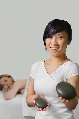 simsearch:625-00901115,k - Close-up of a massage therapist holding two pebbles with a mature woman lying on a massage table behind her Stock Photo - Premium Royalty-Free, Code: 625-02267420