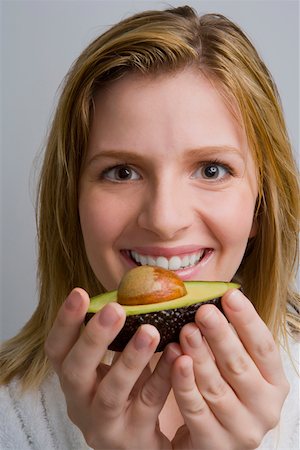 schoolchild eat - Portrait of a teenage girl holding an avocado and smiling Stock Photo - Premium Royalty-Free, Code: 625-02267599