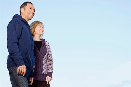 senior couple multicultural - Low angle view of a mature couple standing and smiling Stock Photo - Premium Royalty-Free, Code: 625-02267679