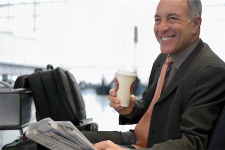 Side profile of a businessman sitting at an airport and smiling Stock Photo - Premium Royalty-Free, Code: 625-02267685