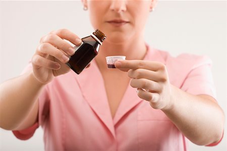 Female nurse pouring syrup into a bottle cap Foto de stock - Sin royalties Premium, Código: 625-02267703