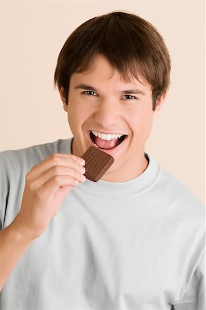 Portrait of a young man eating a biscuit Stock Photo - Premium Royalty-Free, Code: 625-02267710