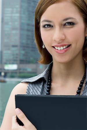 Portrait of a businesswoman holding a ring binder and smiling Stock Photo - Premium Royalty-Free, Code: 625-02267736