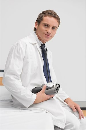 simsearch:700-00022316,k - Portrait of a male doctor sitting on the bed and holding a blood pressure gauge Stock Photo - Premium Royalty-Free, Code: 625-02267812