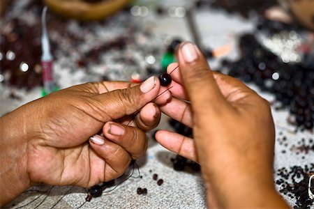 Close-up of a person's hands making beaded jewelry, Izamal, Yucatan, Mexico Stock Photo - Premium Royalty-Free, Code: 625-02267949