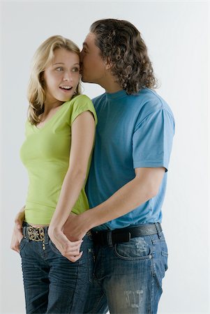 Young man whispering into a young woman's ear Foto de stock - Royalty Free Premium, Número: 625-02927076