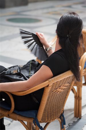 Side profile of a woman sitting on chair and holding a folding fan, Naples, Naples Province, Campania, Italy Stock Photo - Premium Royalty-Free, Code: 625-02927608