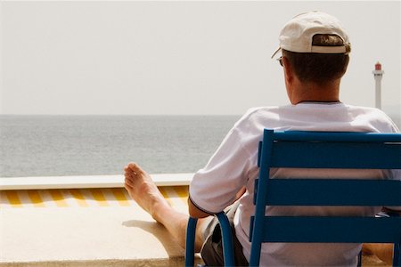 simsearch:625-02928803,k - Rear view of a man sitting in an armchair on the beach, Baie De Cannes, Provence-Alpes-Cote D'Azur, France Fotografie stock - Premium Royalty-Free, Codice: 625-02928913