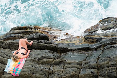 High angle view of a woman lying on cliff, RioMaggiore, Cinque Terre, Italian Riviera, Cinque Terre National Park, Vernazza, La Spezia, Liguria, Italy Stock Photo - Premium Royalty-Free, Code: 625-02928934