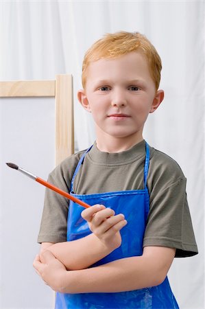 Portrait of a schoolboy holding a paintbrush and smiling Stock Photo - Premium Royalty-Free, Code: 625-02929001