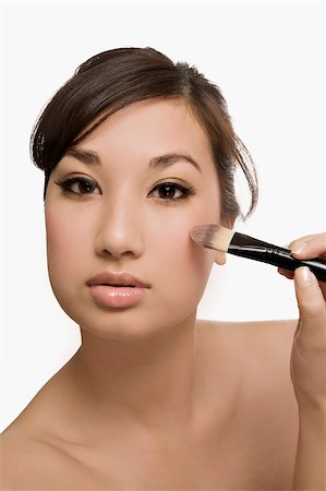 simsearch:625-02267557,k - Portrait of a young woman holding a make-up brush Stock Photo - Premium Royalty-Free, Code: 625-02929024