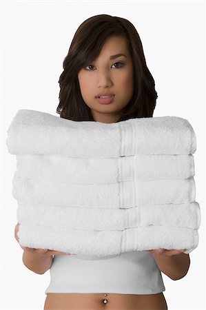 folded towels - Portrait of a young woman holding a stack of folded towels Stock Photo - Premium Royalty-Free, Code: 625-02929051